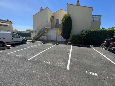 a car parked in a parking lot next to a building at Appartement La Pinède avec Terrasse, clim et parking - GN320-124 in Gruissan