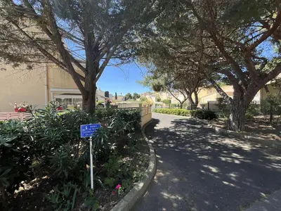 a sign in a park with trees and a building at Appartement La Pinède avec Terrasse, clim et parking - GN320-124 in Gruissan