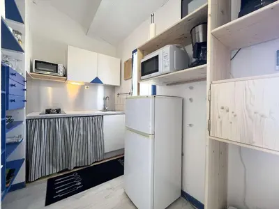 a small kitchen with a refrigerator and cabinets at Appartement La Pinède avec Terrasse, clim et parking - GN320-124 in Gruissan