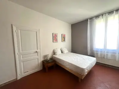 a bedroom with a bed and a door and a window at Centre ville, grand T3 avec balcon in Narbonne