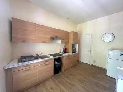 a kitchen with wooden cabinets and a sink and a refrigerator at Centre ville, grand T3 avec balcon in Narbonne