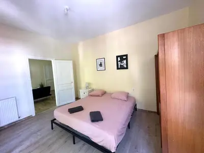 a bedroom with a large bed with pink sheets at Centre ville, grand T3 avec balcon in Narbonne