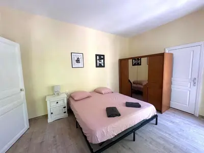 a bedroom with a bed with pink sheets and a mirror at Centre ville, grand T3 avec balcon in Narbonne