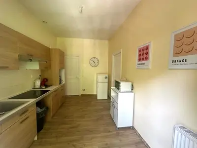 a kitchen with a white refrigerator and a clock on the wall at Centre ville, grand T3 avec balcon in Narbonne