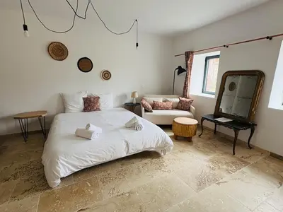 a bedroom with a white bed and a couch at La Métairie du Château Paul in Aussillon