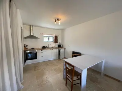 a kitchen with a white table and a white counter top at La Métairie du Château Paul in Aussillon