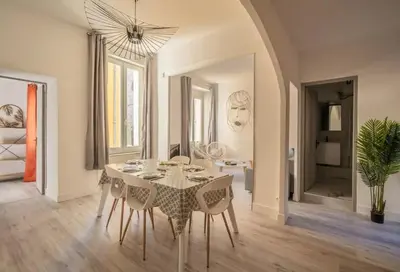 a white dining room with a table and chairs at Cocon des halles - Climatisation - Terrasse in Narbonne