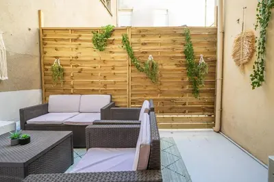 an outdoor patio with a wooden wall with plants at Cocon des halles - Climatisation - Terrasse in Narbonne