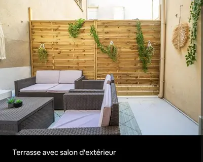 an outdoor patio with a wooden wall with plants at Cocon des halles - Climatisation - Terrasse in Narbonne