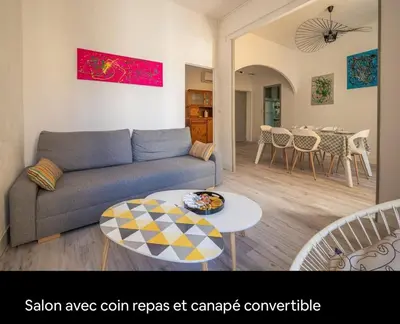a living room with a couch and a table at Cocon des halles - Climatisation - Terrasse in Narbonne