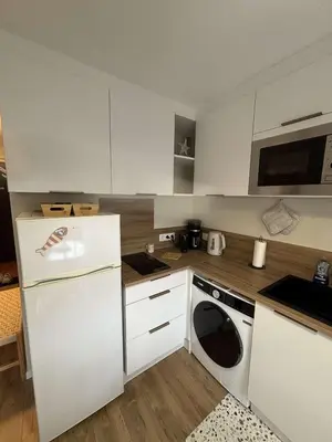 a kitchen with a white refrigerator and a dishwasher at Superbe Appartement T2 climatisé in Gruissan