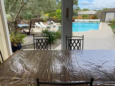 a table and chairs with a view of a pool at Les Oliviers in Villemoustaussou