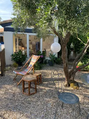 a patio with two chairs and a table and a tree at Les Oliviers in Villemoustaussou