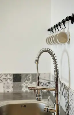 a kitchen sink with a chrome kitchen faucet at Puddington Abbey by Art&Suites Élégant XVIIIe 80m privatif Centre ville Calme et douceur de vivre in Narbonne