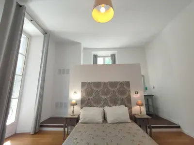 a bedroom with a bed and two tables and two windows at Suite de Rêve au Château avec Bain Caché - Accès Bassin de Nage - Clim in La Redorte