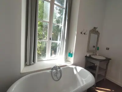 a bathroom with a white tub and a window at Suite de Rêve au Château avec Bain Caché - Accès Bassin de Nage - Clim in La Redorte