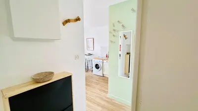 a living room with a television and a hallway with a kitchen at Studio Chanzy lumineux cozy avec terrasse Narbonne in Narbonne