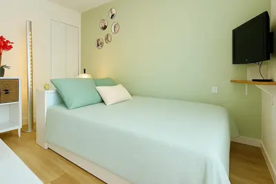 a bedroom with a blue bed with a tv on the wall at Studio Chanzy lumineux cozy avec terrasse Narbonne in Narbonne