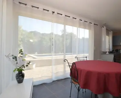 a dining room with a red table and a large window at Villa Alfabeta in Bizanet