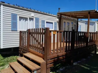 a house with a wooden deck in front of it at Mobilhome tout confort in Port-la-Nouvelle
