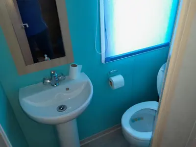 a blue bathroom with a sink and a toilet at Mobilhome tout confort in Port-la-Nouvelle