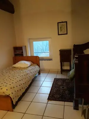 a bedroom with a bed and a window and a tiled floor at Gîte de la Truie qui File in Noailhac
