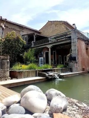 an old building next to a body of water at Gîte de la Truie qui File in Noailhac