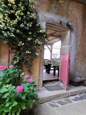 an open doorway to a patio with a bench and flowers at Gîte de la Truie qui File in Noailhac