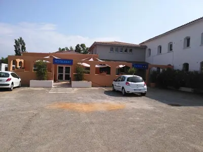 two cars parked in a parking lot in front of a building at Hôtel Le Floreal in Trèbes