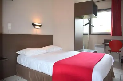 a bedroom with a bed with a red blanket on it at Hôtel Le Floreal in Trèbes