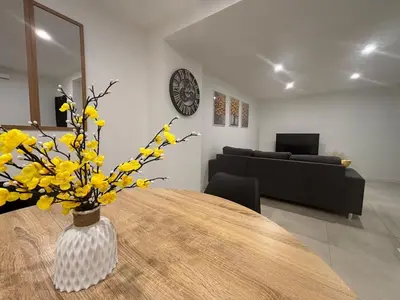 a vase of yellow flowers on a table in a living room at Chez Cricri, modern accommodation in Bizanet