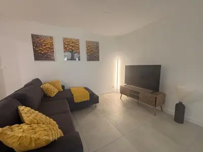 a living room with a couch and a flat screen tv at Chez Cricri, modern accommodation in Bizanet
