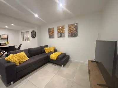 a living room with a black couch and yellow pillows at Chez Cricri, modern accommodation in Bizanet