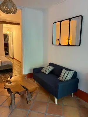 a living room with a blue couch and a wooden table at Appartement avec jardin sous les couverts in Mirepoix