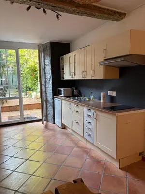 a kitchen with white cabinets and a tile floor at Appartement avec jardin sous les couverts in Mirepoix
