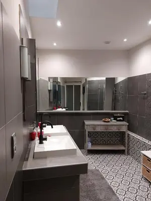 a bathroom with a sink and a large mirror at Jolie maison de village avec vue in Maury