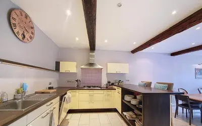 a kitchen with a sink and a clock on the wall at Jolie maison de village avec vue in Maury