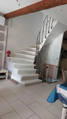 a staircase in a living room with white stairs at Jolie maison de village avec vue in Maury