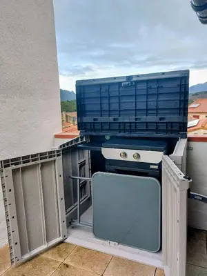 a kitchen with a stove and a tv on a balcony at Jolie maison de village avec vue in Maury