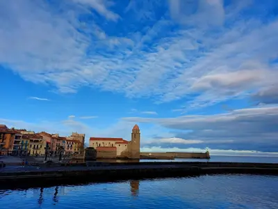 a building with a clock tower next to a body of water at Jolie maison de village avec vue in Maury