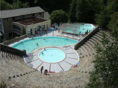 a large swimming pool with people sitting around it at Jolie maison de village avec vue in Maury
