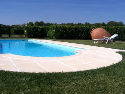 a swimming pool in the grass with a chair next to it at Charming farmhouse gite in southwestern France in Montferrand