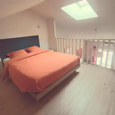 a bedroom with a bed with an orange comforter at Pipa in Narbonne