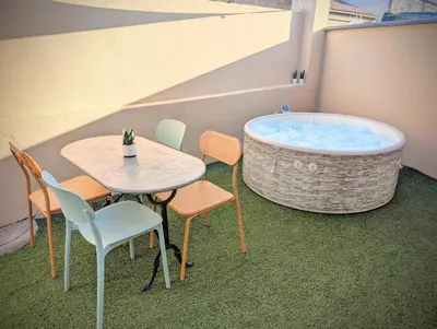 a table and chairs next to a bath tub at 151 - Terrasse & Jacuzzi, Rue Trivalle, Pied de la cité de Carcassonne - Climatisation, Netflix, Fibre in Carcassonne