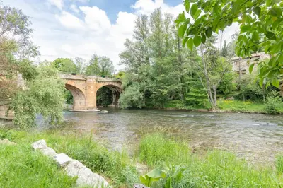 a stone bridge over a river with a bridge at La Campagnarde - Avec jardin clos in Campagne-sur-Aude
