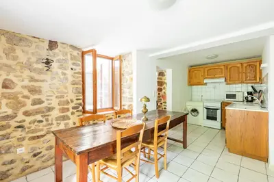a kitchen with a wooden table and chairs at La Campagnarde - Avec jardin clos in Campagne-sur-Aude