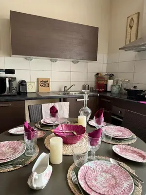 a table in a kitchen with pink dishes on it at Les gites du tilleul in Villefranche-de-Lauragais