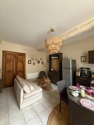 a living room with a white couch and a kitchen at Les gites du tilleul in Villefranche-de-Lauragais