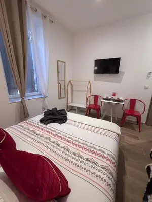 a bedroom with two beds and a table with red chairs at La Rubis in Narbonne