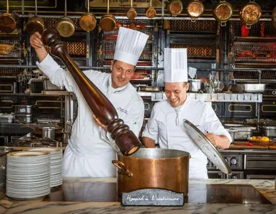 two chefs in a kitchen preparing food in a pot at Le Chenal - Appartement Duplex proche des halles in Narbonne
